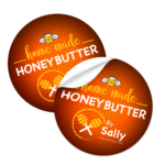 Die-cut sticker featuring "homemade honey butter by Sally" with a honey dipper design, showcasing vibrant orange background and appealing typography, relevant to Design One Printing's custom sticker services.