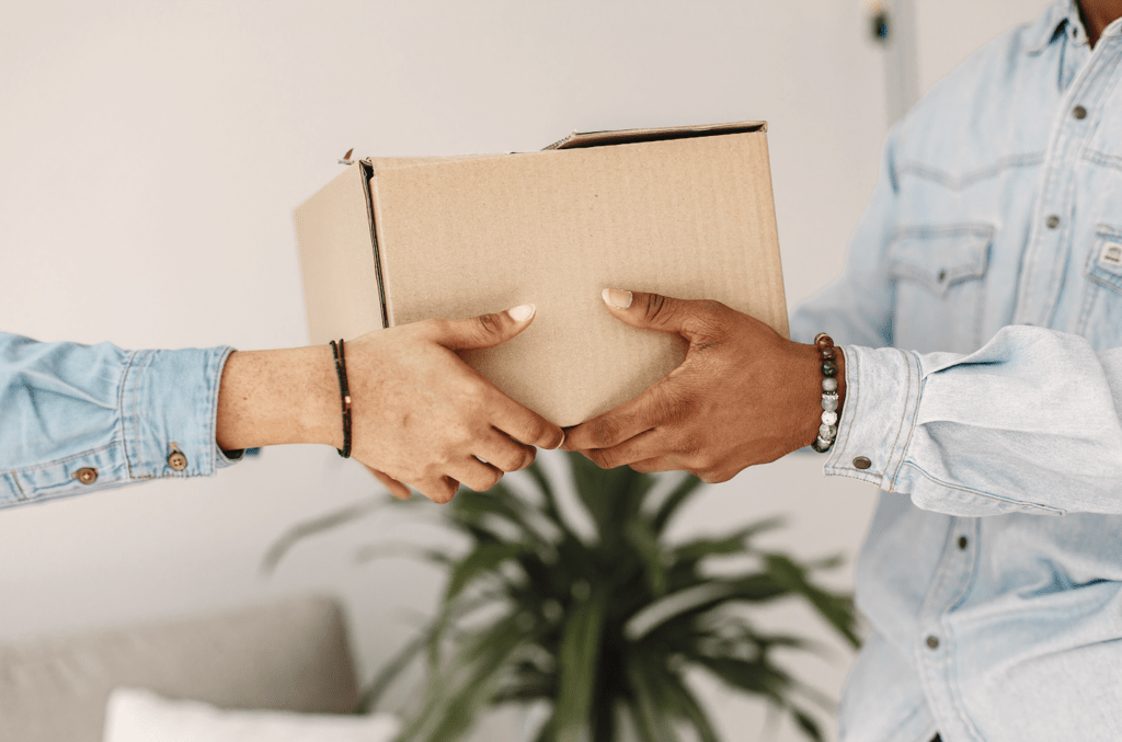 Hands exchanging a cardboard box, symbolizing same day printing delivery service by Design One Printing.