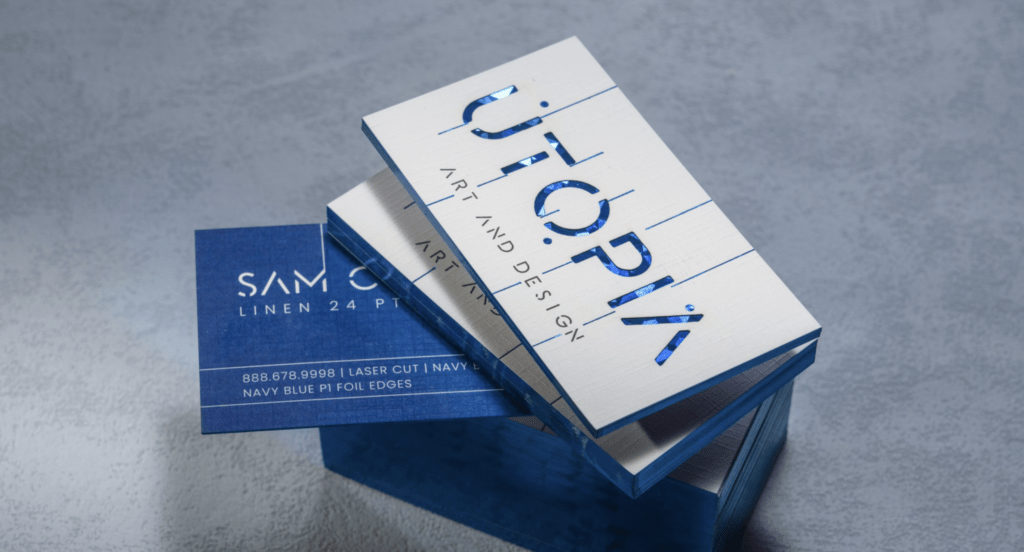 Business cards featuring UTOPIK Art and Design with a sleek, metallic finish and navy blue accents, showcasing modern design elements relevant to commercial printing services.