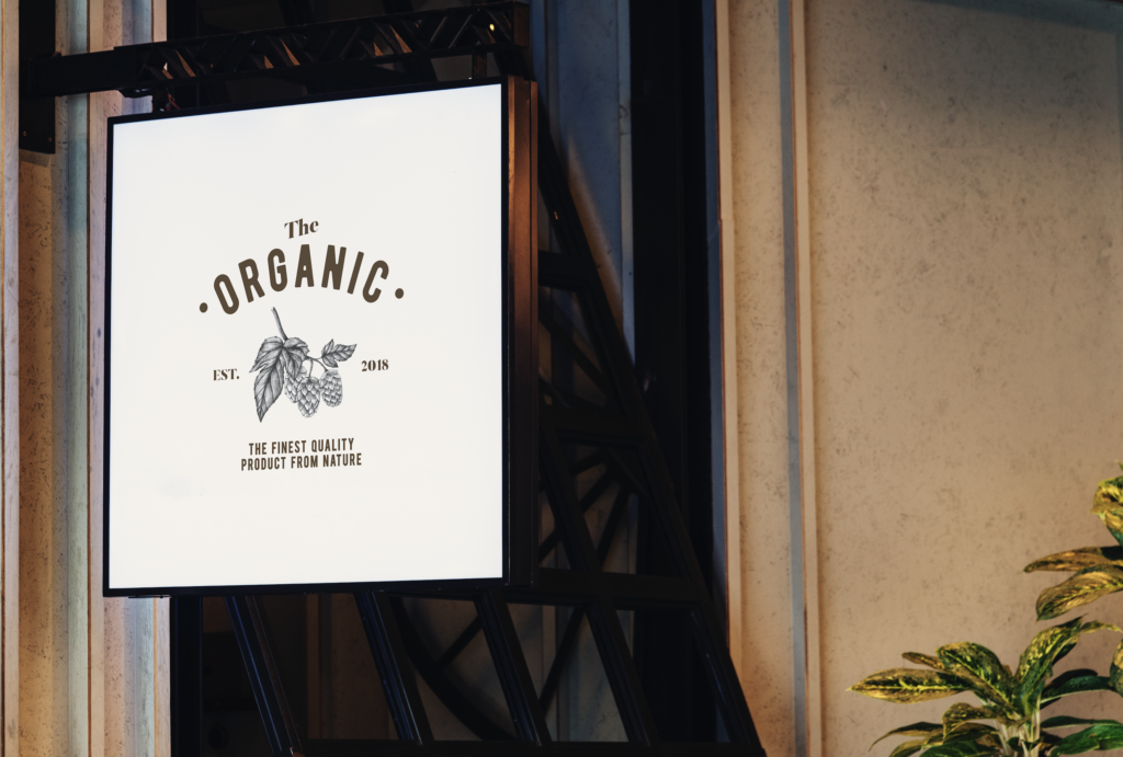 Illuminated sign displaying "The Organic" with a graphic of leaves and berries, emphasizing quality and nature, relevant to promotional products and printing services.