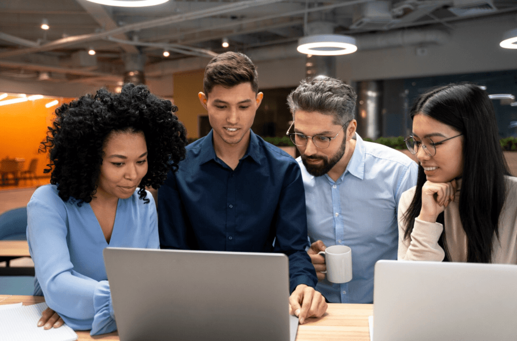 Group collaborating around a laptop in a modern office setting, discussing on-demand printing solutions and design products.