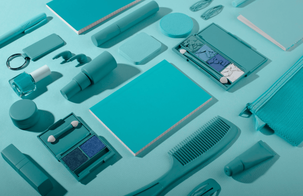 Colorful assortment of promotional products including notebooks, cosmetics, and stationery items in teal tones, reflecting Design One Printing's focus on promotional products.