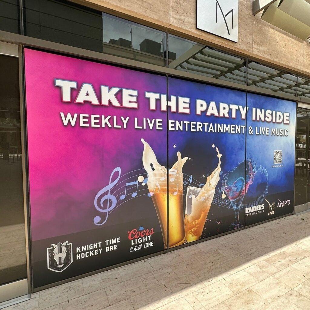 Window graphic promoting live entertainment and music at Knight Time Hockey Bar, featuring colorful design with beer glasses, musical notes, and text "Take the Party Inside" along with logos for Coors Light and Raiders Tavern & Grill.